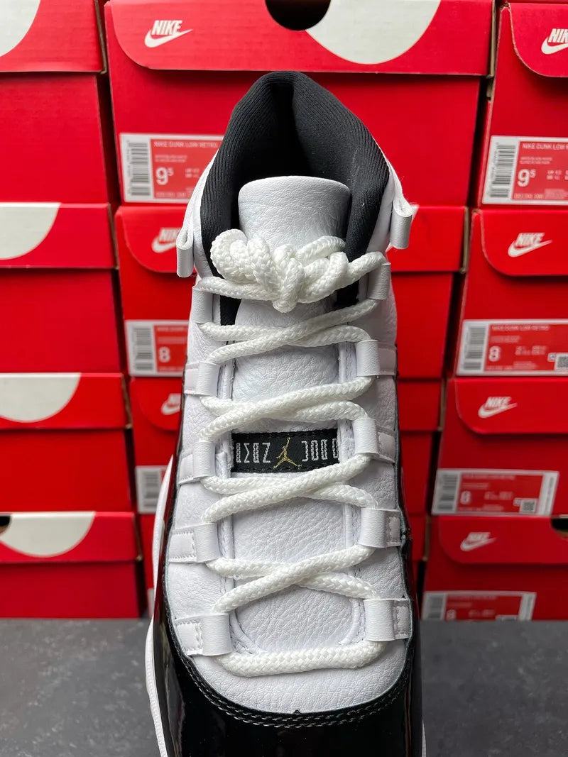 White Air Jordan 11 high-top sneaker with white laces and black toe panel