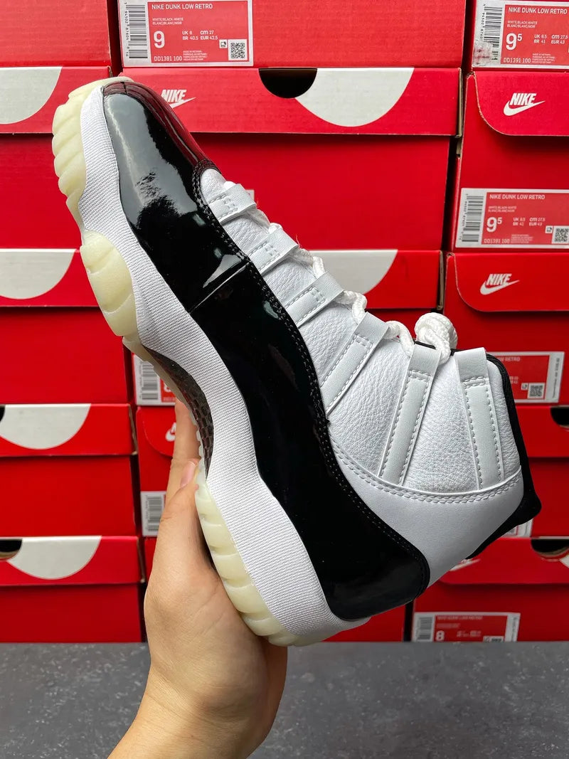 White and black Air Jordan 11 high-top sneaker, glossy black panel and cream sole