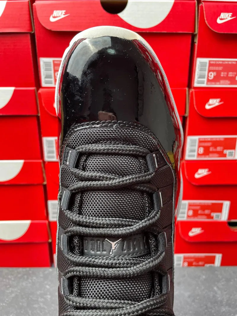 Black sneaker front with lace-up cords and stitched puma-style logo detail