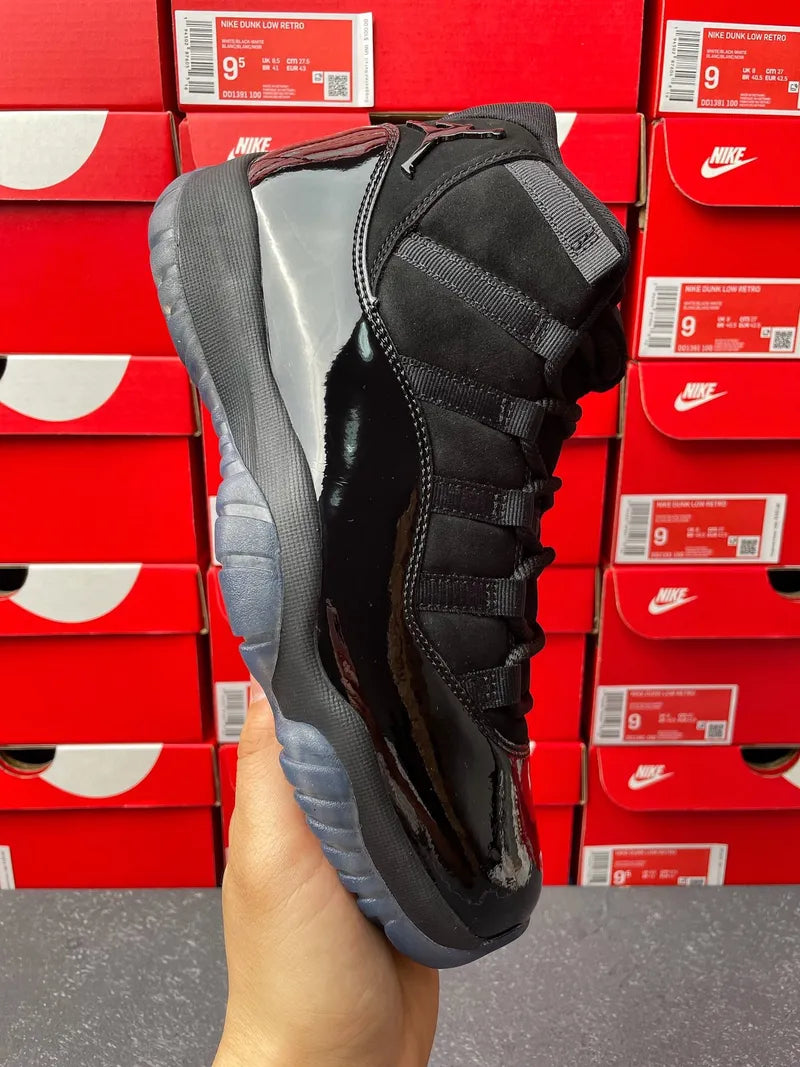 Air Jordan 11 high-top sneaker, side view in black with strap lacing and gray sole