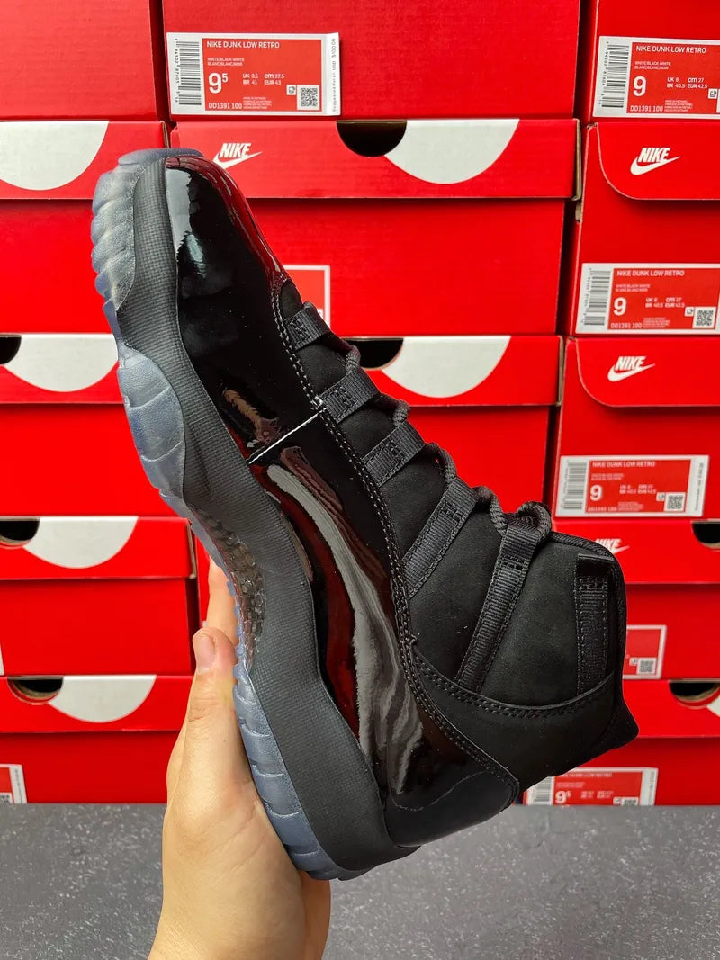 Air Jordan 11 sneaker, angled view in black with glossy accents and gray sole