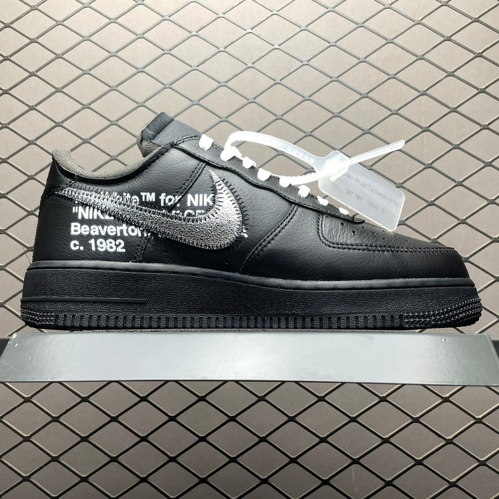 Black low-top sneaker with large white swoosh and side text embroidery