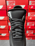Black lace-up sneaker with textured midsole and woven upper, front view