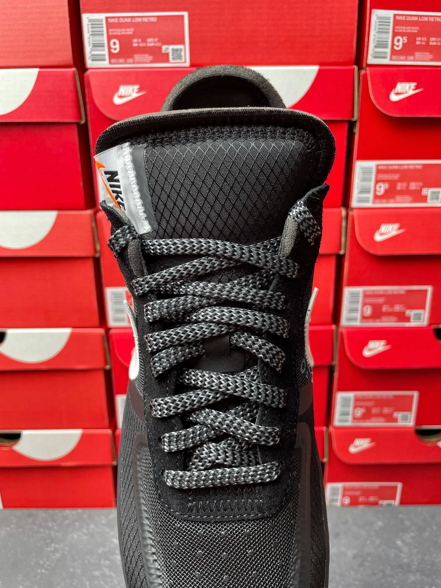 Black lace-up sneaker with textured midsole and woven upper, front view