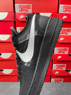 Black low-top sneaker with white swoosh, mesh sides, black laces, angled side view