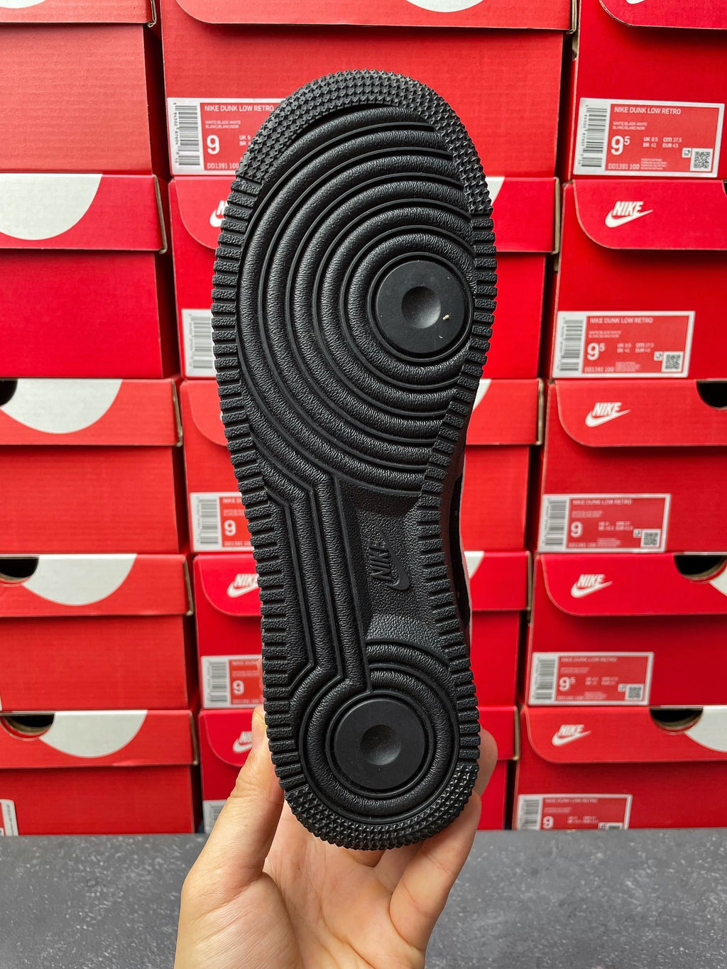 Black sneaker outsole underside with circular traction pattern, heel-to-toe view