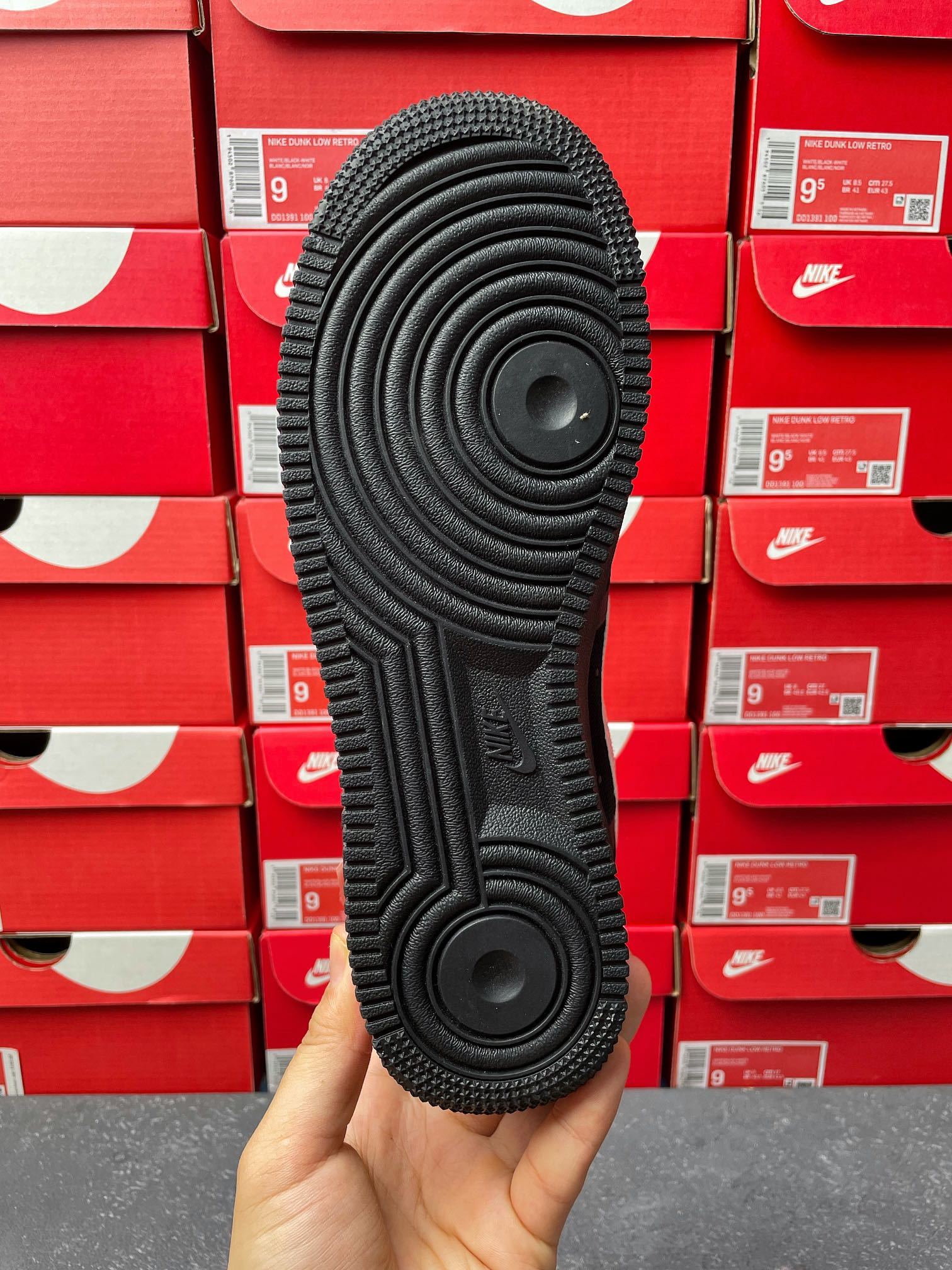 Black sneaker outsole underside with circular traction pattern, heel-to-toe view
