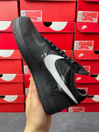 Black low-top sneaker with white swoosh and textured sole, angled heel-to-side view