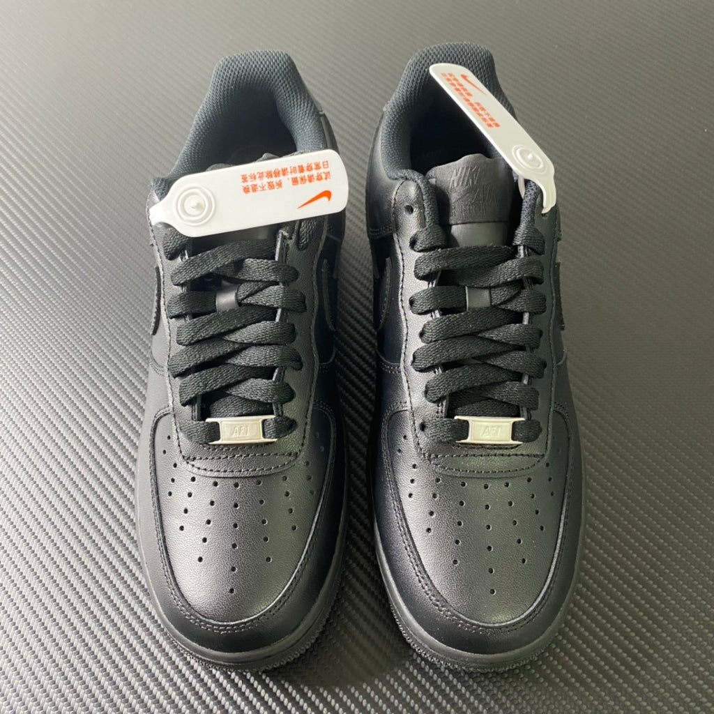 Nike Air Force 1 sneakers pair, front view with perforated toe and lace-up front, dark.