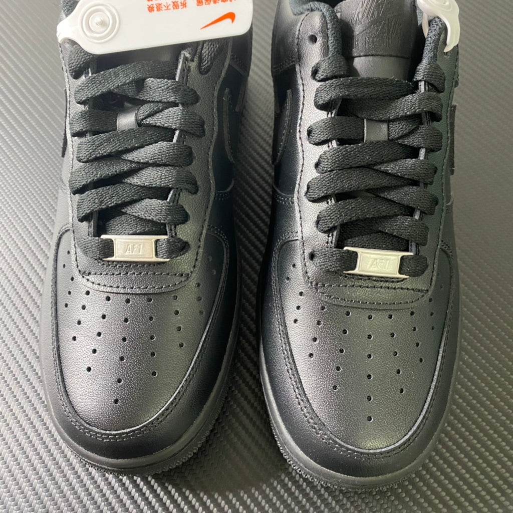 Nike Air Force 1 sneakers pair, close-up of lace area and perforated toe, dark leather.