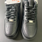 Nike Air Force 1 sneakers pair, close-up of lace area and perforated toe, dark leather.