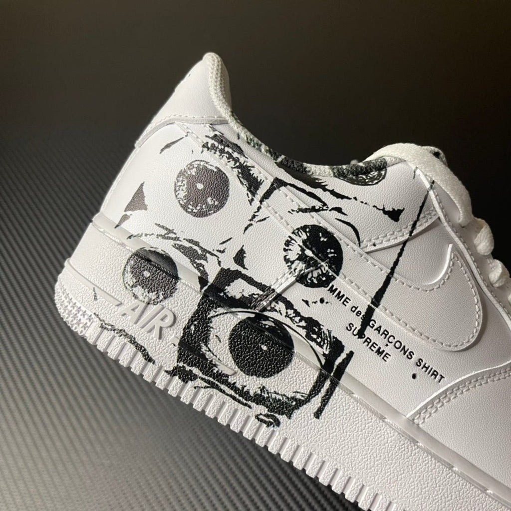 White low-top sneaker with black graphic wrap around laces and swoosh