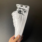 White low-top sneaker held by hand, showing black graphic print near toe