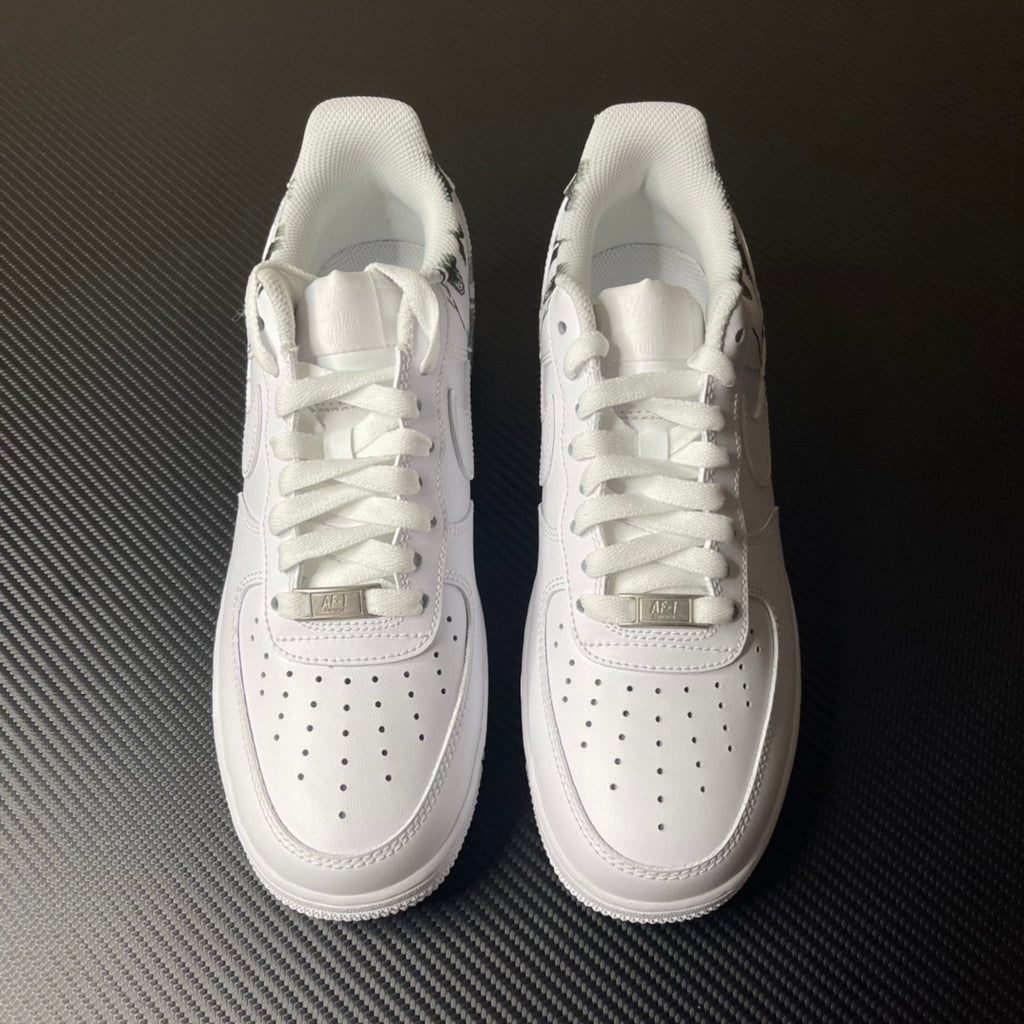 White low-top sneakers with lace-up closure, swoosh logos, and perforated toe