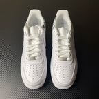 White low-top sneakers with lace-up closure, swoosh logos, and perforated toe