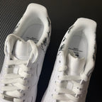 White low-top sneakers with white laces and printed insoles at heel