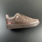 Taupe low-top sneakers with swoosh, lace-up, Supreme patch, and 'AIR' midsole detail.