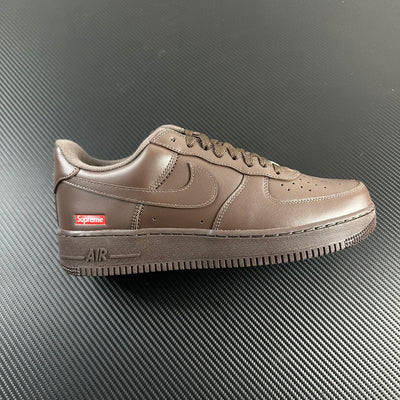 Taupe low-top sneakers with swoosh, lace-up, Supreme patch, and 'AIR' midsole detail.