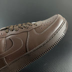 Taupe low-top sneaker side close-up with swoosh and lace eyelets, perforated toe.