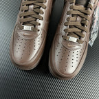 Taupe low-top sneakers top view with lace-up, perforated toe, and side swooshes.