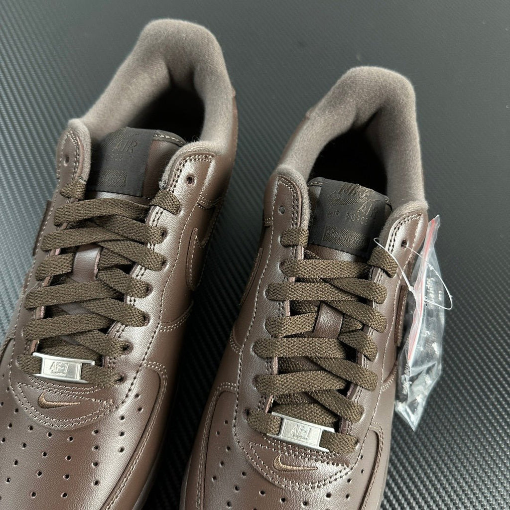 Taupe low-top sneakers front view showing laces, perforations, and side swooshes.
