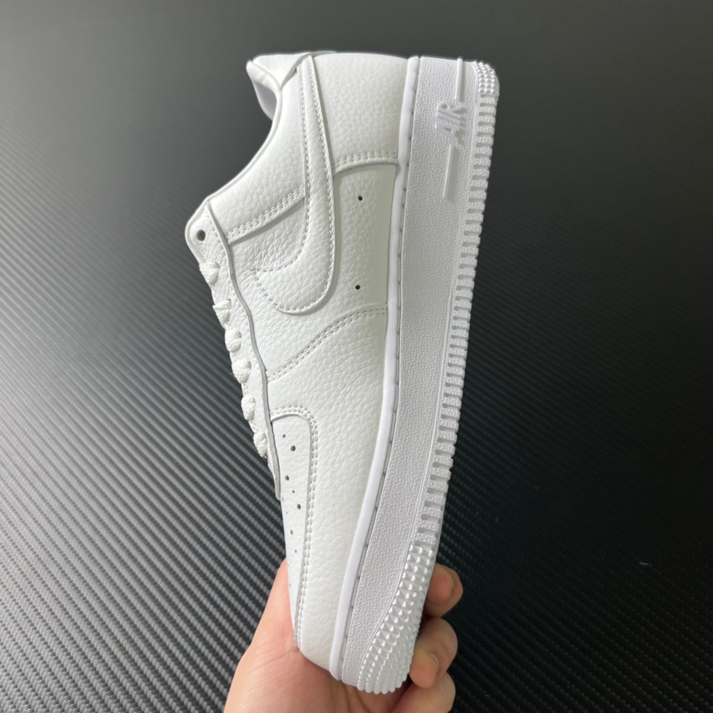 White low-top sneakers held in hand, showing side profile and textured sole
