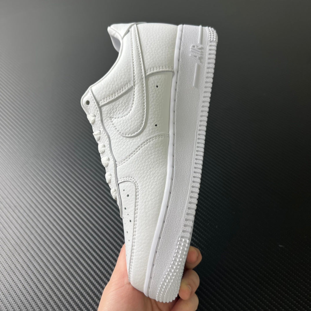 White low-top sneakers held in hand, showing side profile and textured sole