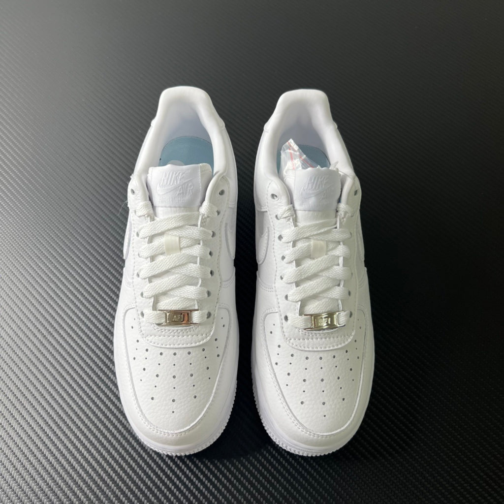 Pair of white low-top sneakers with lace-up closure and buckle strap