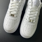White sneakers front close-up with perforations and gold-toned buckle straps