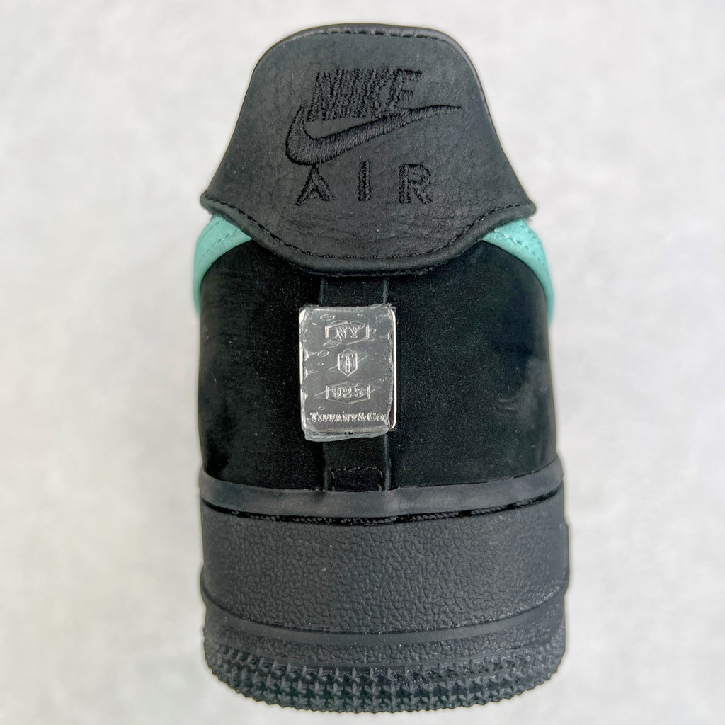 Air Force 1 heel close-up in black with teal accent and metal tag.