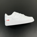 White low-top sneakers with perforated toe and red side Supreme label
