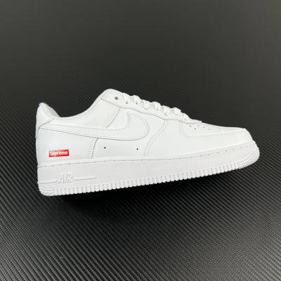 White low-top sneakers with perforated toe and red side Supreme label