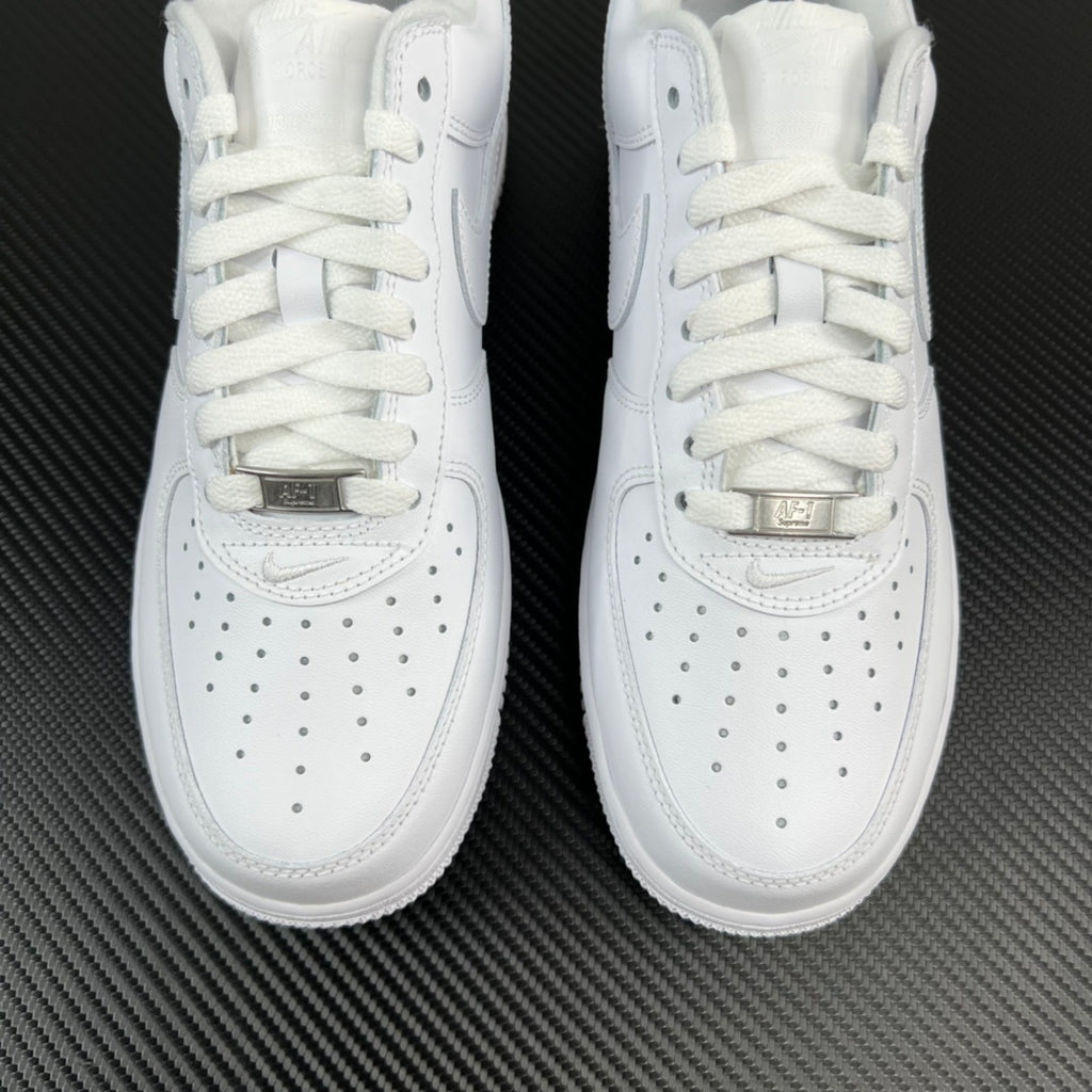 Front view of white low-top sneakers with gold-tone lace tag