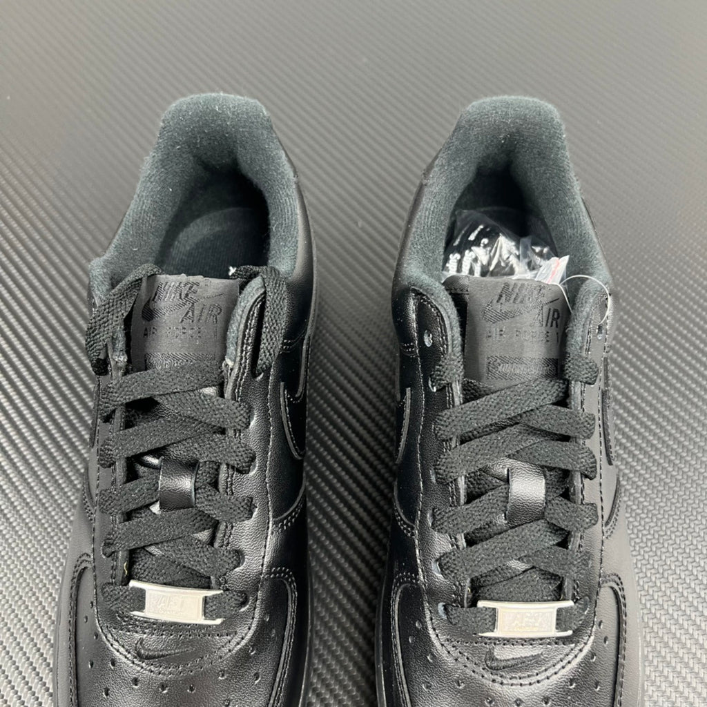 Pair of dark lace-up sneakers with perforated toe and padded collar