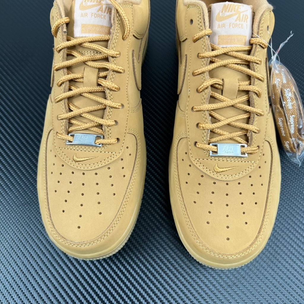Pair of yellow Air Force 1 sneakers with lace-up panels and blue lace accents