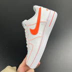 White low-top sneaker with orange Swoosh and stitched overlays, held in hand.