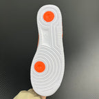 White rubber outsole with orange traction pods, sneaker bottom view.