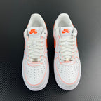 Pair of white low-top sneakers with orange accents, lace-up front view.
