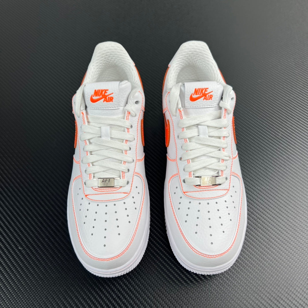 Pair of white low-top sneakers with orange accents, lace-up front view.