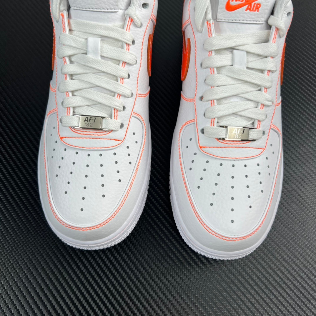 Two white lace-up sneakers with orange piping and perforated toe panels.