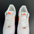 Two white sneakers with orange Swoosh on tongue and perforated toe panels.