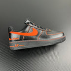 Black and silver Air Force 1 sneaker with orange swoosh and contrast stitching
