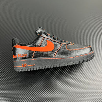 Black and silver Air Force 1 sneaker with orange swoosh and contrast stitching