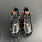 Pair of black and silver Air Force 1 sneakers with orange swooshes and laces