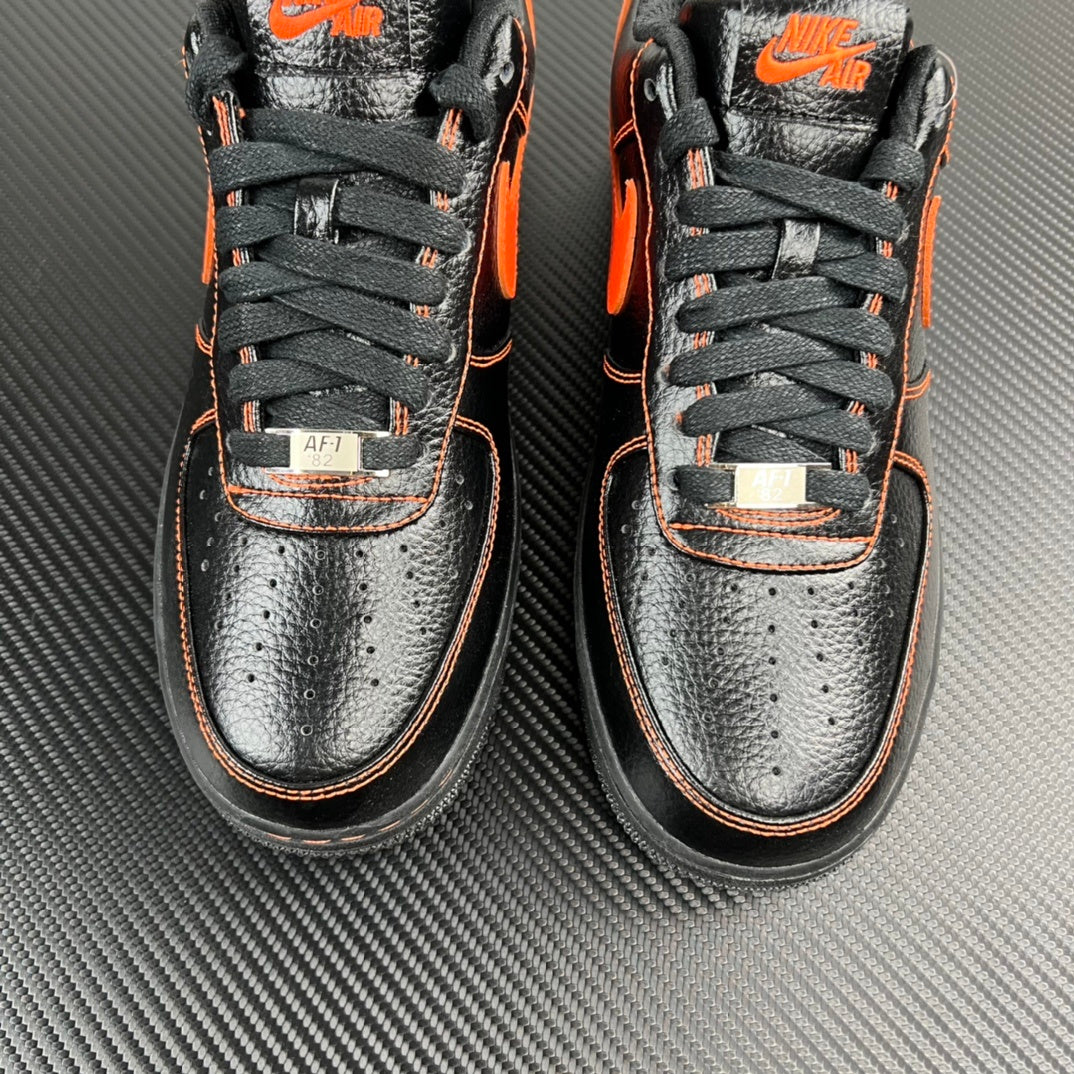 Close front view of black and silver Air Force 1 sneakers with orange swoosh