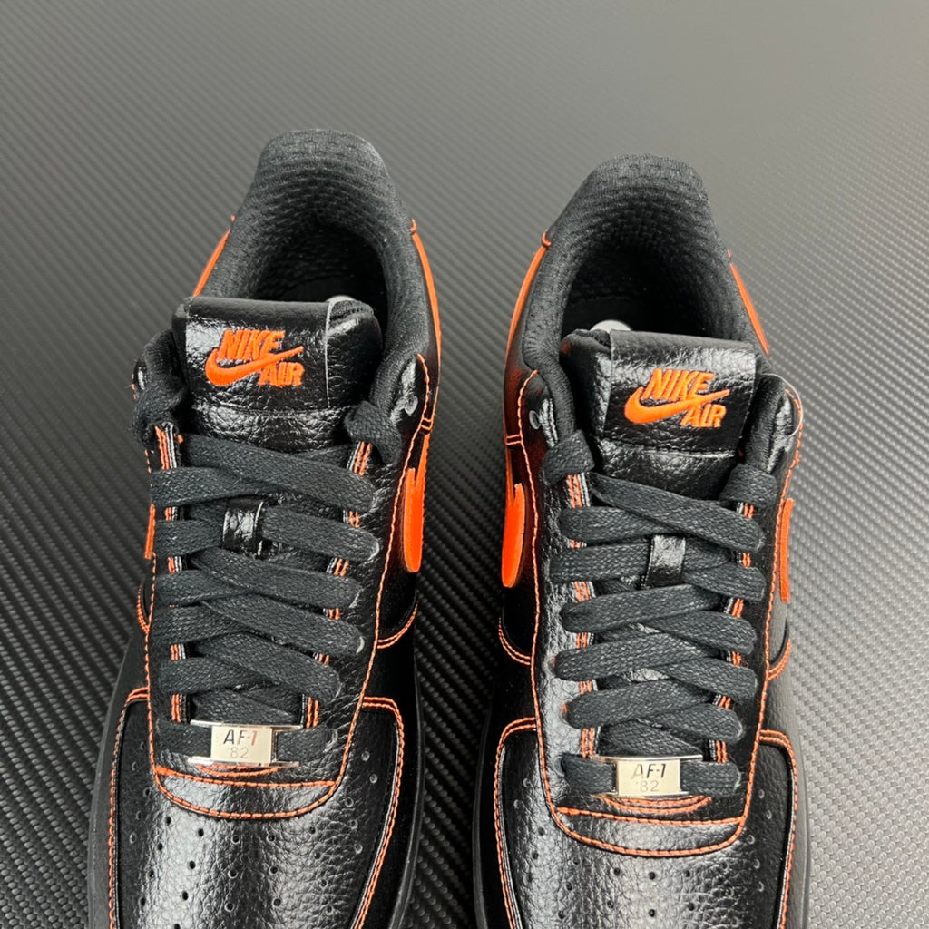 Front view of black and silver Air Force 1 sneakers with orange accents and AF1 tags