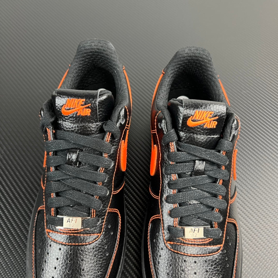 Front view of black and silver Air Force 1 sneakers with orange accents and AF1 tags