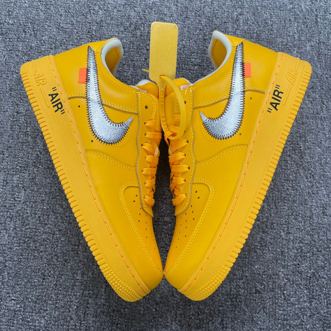 Pair of yellow Air Force 1 sneakers with white swooshes and lace-up fronts