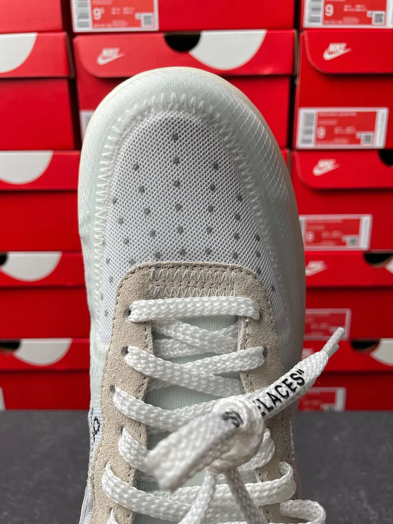 Off-white front view of sneaker with lace-up ties and perforated toe box