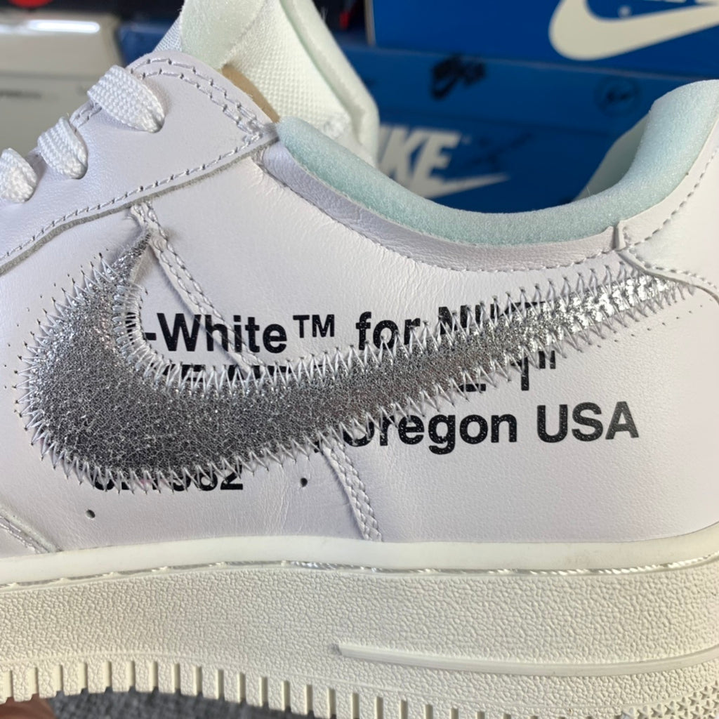 White sneaker side close-up with metallic swoosh and OFF-WHITE™ text